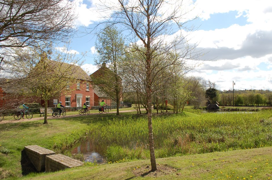 An attenuation basin is designed as a focal feature akin to a village green, safely incorporated into open space with no requirement for fencing. The feature serves a multi-functional purpose for biodiversity.